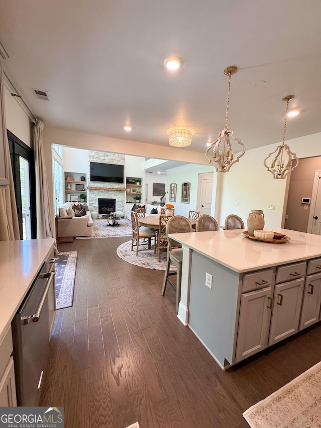 4736 Landing Water Path, Buford, GA 30519 - kitchen with dark wood-style flooring, a stone fireplace, a kitchen breakfast bar, gray cabinetry, and light countertops