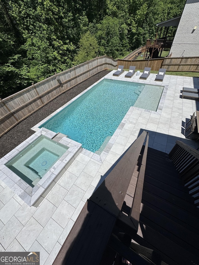 4736 Landing Water Path, Buford, GA 30519 - view of swimming pool featuring a patio area, a pool with connected hot tub, a fenced backyard, and a forest view