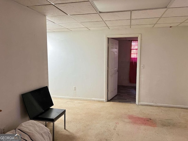 living area featuring a paneled ceiling and baseboards