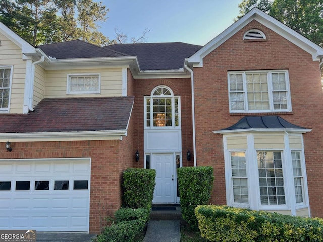 view of front facade featuring brick siding, roof with shingles, and a garage