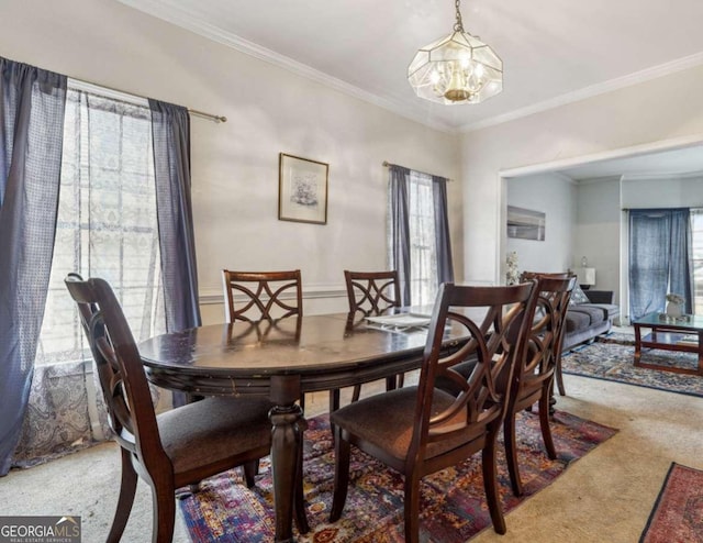 dining room with light carpet, a chandelier, and ornamental molding