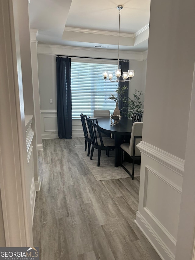 3006 Fairway Dr, Villa Rica, GA 30180 - dining room featuring a raised ceiling, crown molding, a chandelier, wood finished floors, and a decorative wall
