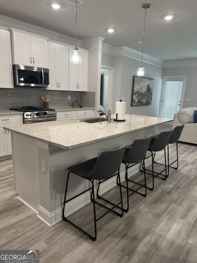 3006 Fairway Dr, Villa Rica, GA 30180 - kitchen featuring appliances with stainless steel finishes, light wood-style floors, white cabinets, backsplash, and ornamental molding