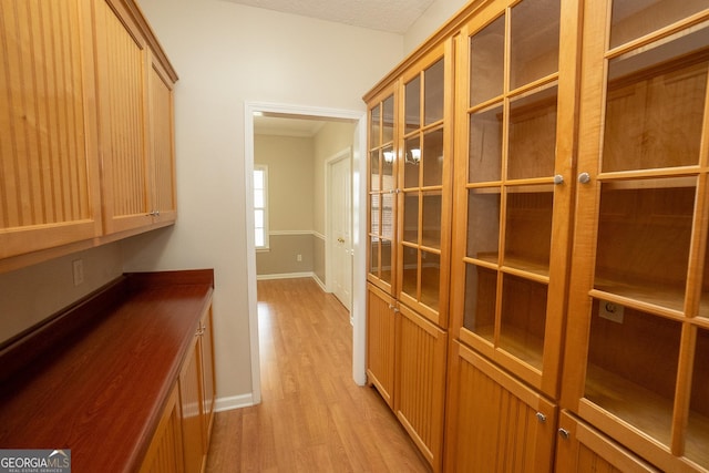 corridor with light wood-style floors, baseboards, crown molding, and french doors