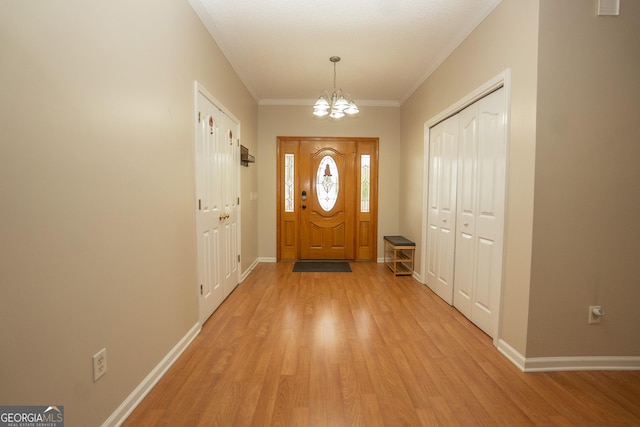 foyer entrance with a chandelier, light wood-style flooring, baseboards, and ornamental molding