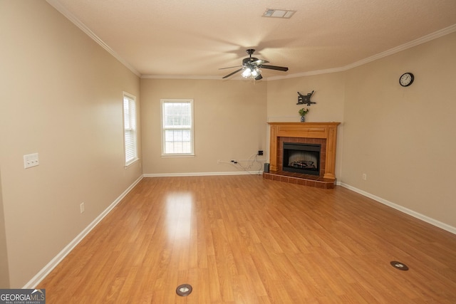 unfurnished living room featuring ceiling fan, light wood-style floors, a tile fireplace, baseboards, and ornamental molding