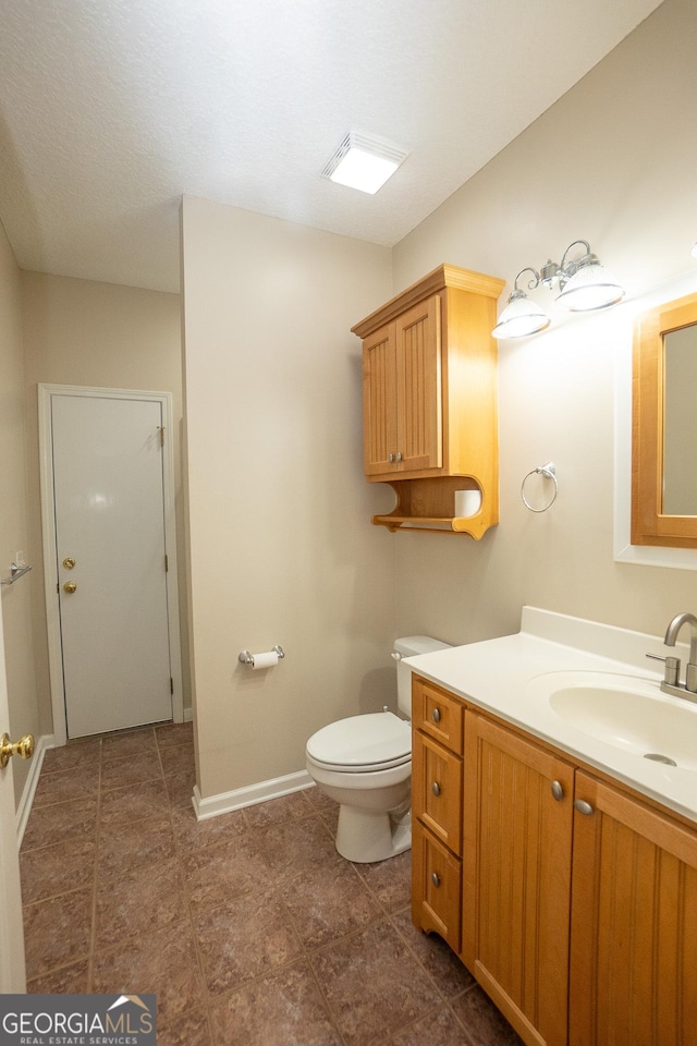 bathroom with baseboards, toilet, and vanity