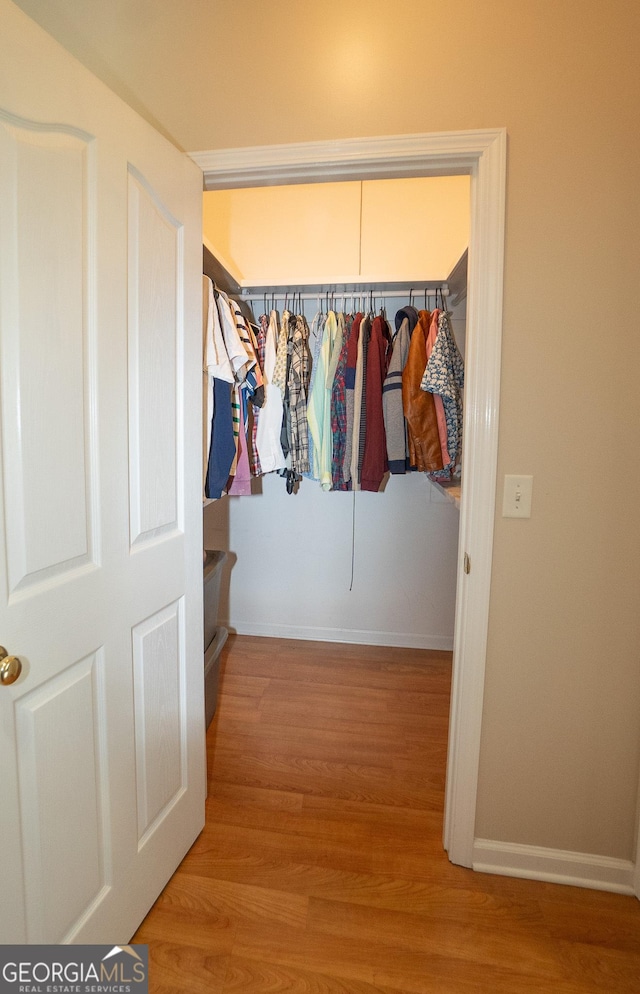 walk in closet with wood finished floors