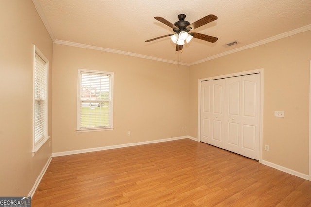 unfurnished bedroom featuring light wood-style flooring, crown molding, a closet, baseboards, and a ceiling fan