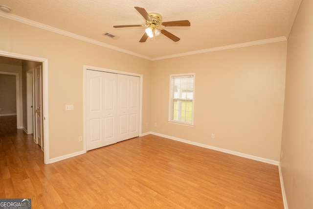 unfurnished bedroom featuring light wood-style floors, ornamental molding, a textured ceiling, baseboards, and a closet