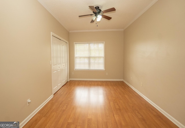 unfurnished bedroom with light wood-style floors, baseboards, crown molding, a closet, and a ceiling fan