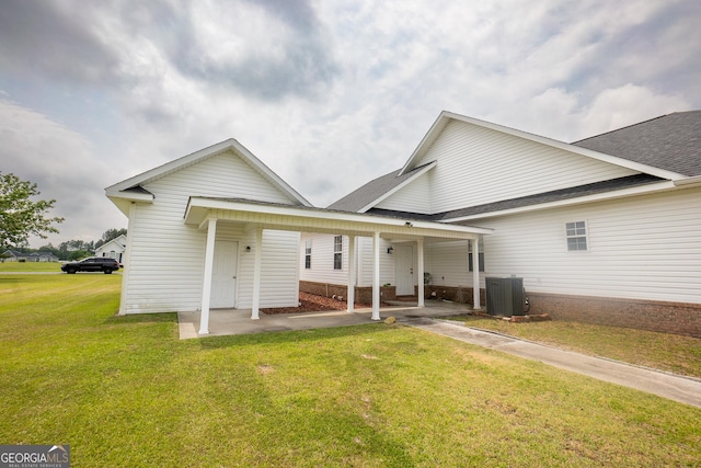 rear view of property with a yard, central AC, and roof with shingles