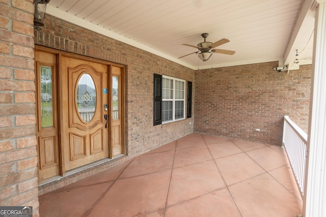 property entrance featuring ceiling fan, brick siding, and covered porch