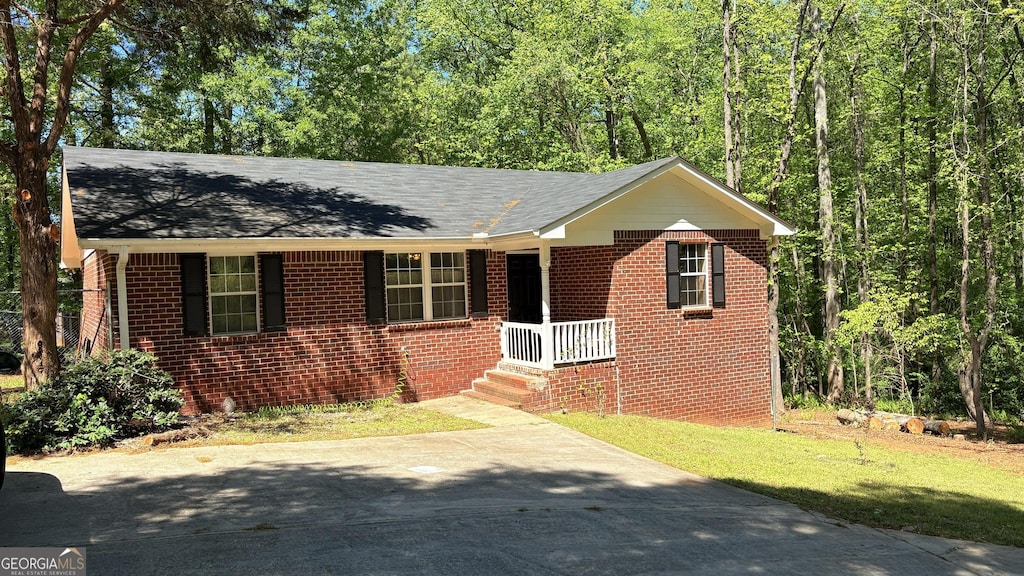 bungalow-style home featuring brick siding, roof with shingles, driveway, and a front yard