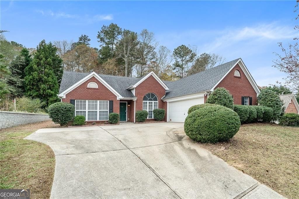 5981 Williamsport Dr, Flowery Branch, GA 30542 - view of front of home featuring brick siding, concrete driveway, a garage, and roof with shingles