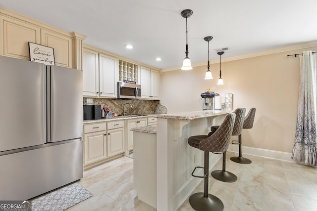 11 Main St, Newnan, GA 30263 - kitchen featuring stainless steel appliances, cream cabinets, decorative backsplash, a kitchen bar, and light stone countertops