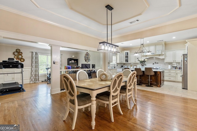 11 Main St, Newnan, GA 30263 - dining space featuring a raised ceiling, light wood-style flooring, crown molding, and decorative columns