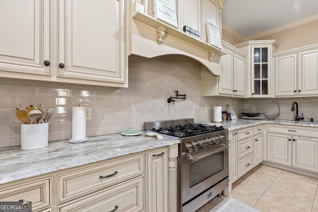 11 Main St, Newnan, GA 30263 - kitchen featuring high end range, a sink, cream cabinetry, tasteful backsplash, and glass insert cabinets