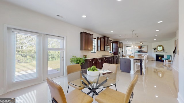 dining area with a ceiling fan, recessed lighting, light tile patterned floors, a lit fireplace, and baseboards