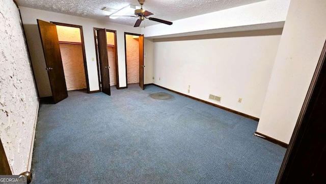 unfurnished bedroom featuring carpet, a textured ceiling, two closets, a ceiling fan, and baseboards