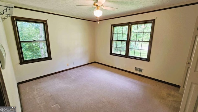 empty room featuring carpet, a textured ceiling, a ceiling fan, baseboards, and ornamental molding
