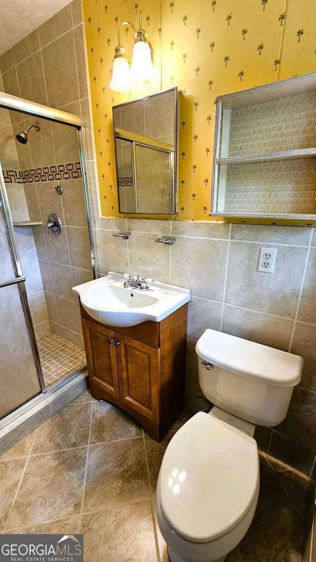full bathroom with a stall shower, tile walls, toilet, and vanity
