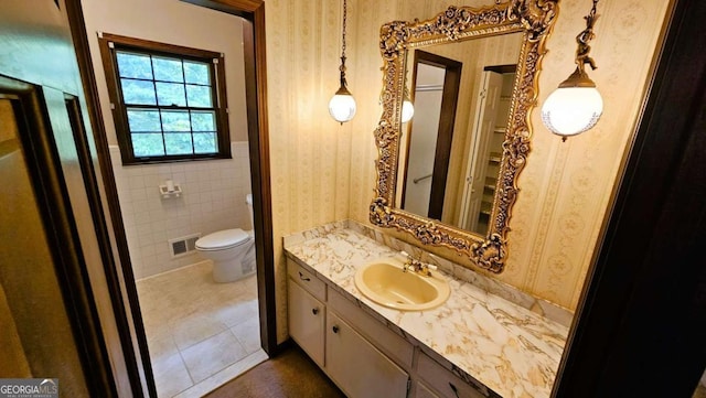 bathroom featuring wallpapered walls, vanity, tile patterned floors, a wainscoted wall, and toilet