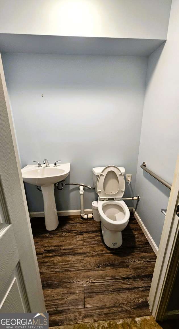 half bath with wood finished floors, toilet, and baseboards