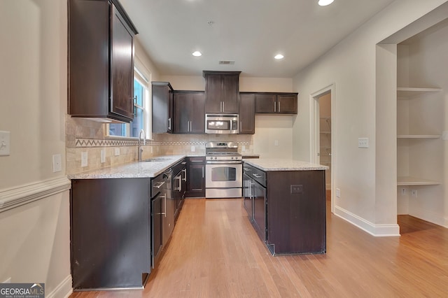 kitchen featuring appliances with stainless steel finishes, a sink, dark brown cabinetry, light wood-type flooring, and recessed lighting