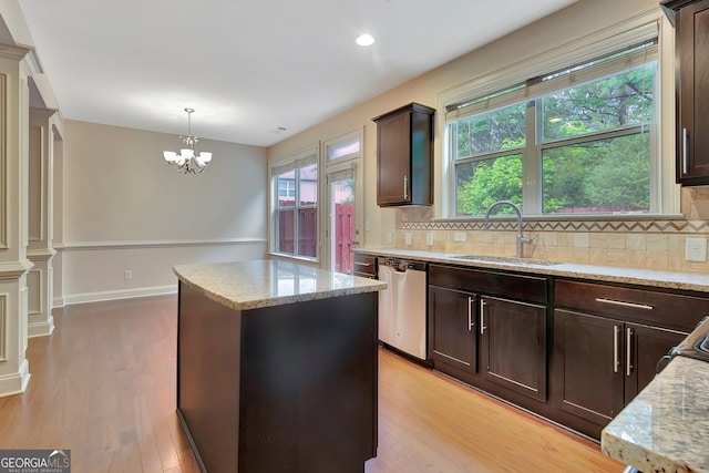 kitchen with a sink, dishwasher, a kitchen island, tasteful backsplash, and light wood-type flooring