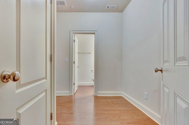 corridor featuring light wood-style flooring and baseboards