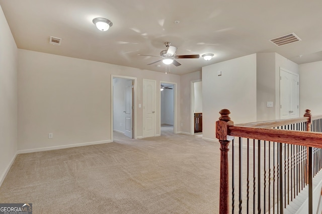 empty room featuring baseboards, light carpet, and ceiling fan