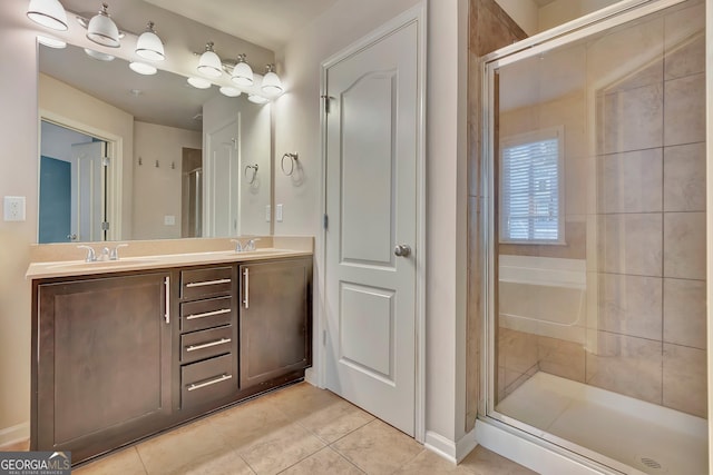 bathroom with tile patterned flooring, a stall shower, double vanity, and baseboards