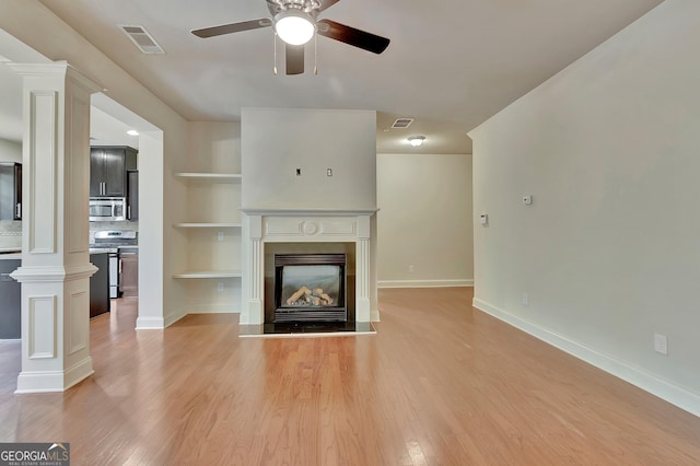 unfurnished living room with decorative columns, a ceiling fan, and light wood-style flooring