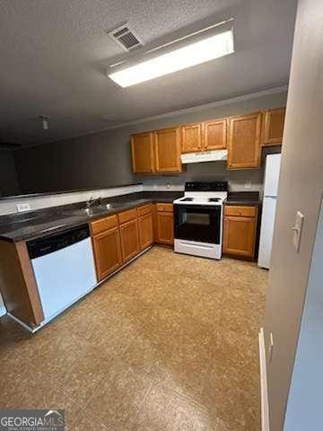 146-148 Arnold Rd, Gray, GA 31032 - kitchen with white appliances, under cabinet range hood, dark countertops, light flooring, and brown cabinets