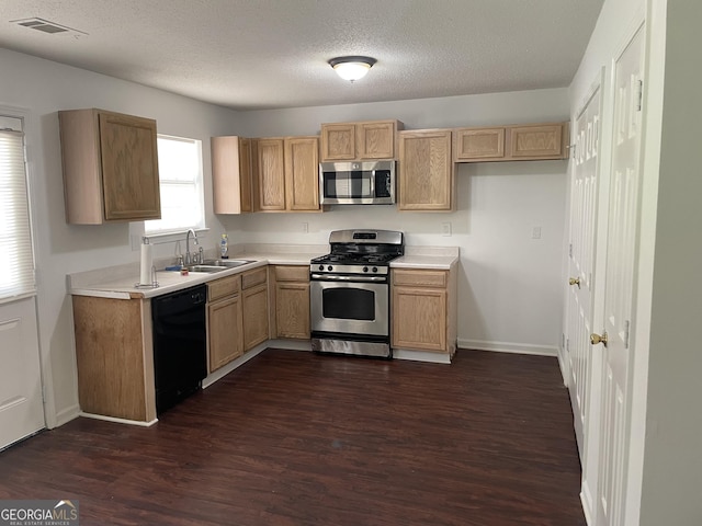 kitchen with stainless steel appliances, a sink, dark wood finished floors, light countertops, and a textured ceiling