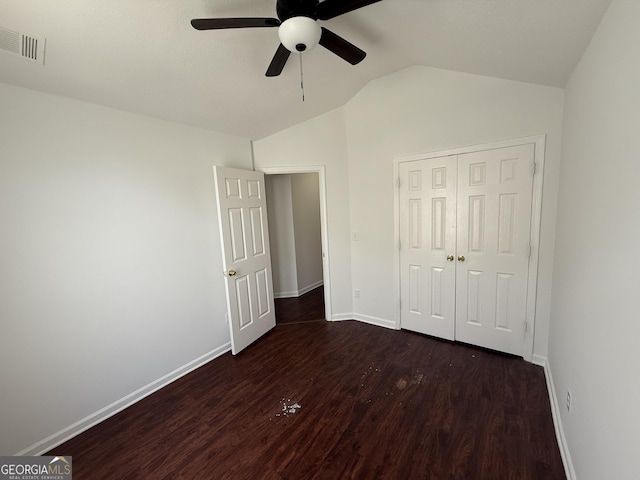 unfurnished bedroom with dark wood-style floors, lofted ceiling, baseboards, a closet, and a ceiling fan