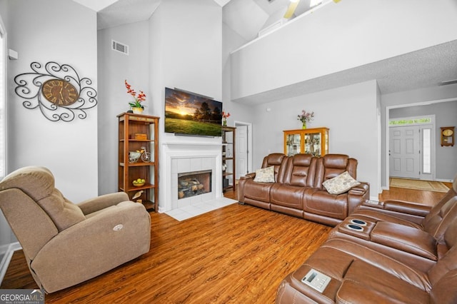 living area featuring wood finished floors, a high ceiling, and a fireplace