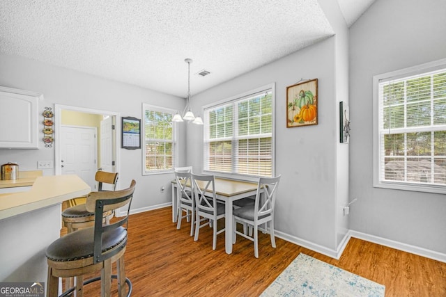dining area with wood finished floors, a textured ceiling, baseboards, and a chandelier