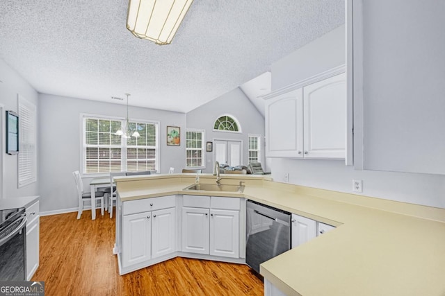kitchen featuring appliances with stainless steel finishes, a sink, a peninsula, light wood-style flooring, and a textured ceiling