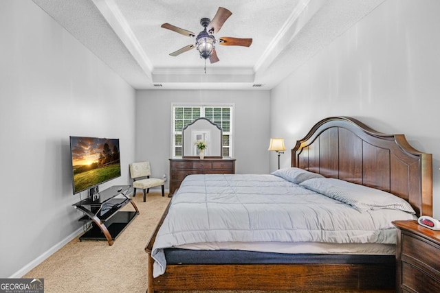 carpeted bedroom with a tray ceiling, baseboards, and a ceiling fan