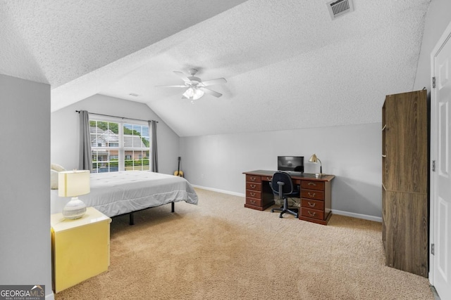 bedroom with a textured ceiling, lofted ceiling, carpet floors, a desk, and a ceiling fan