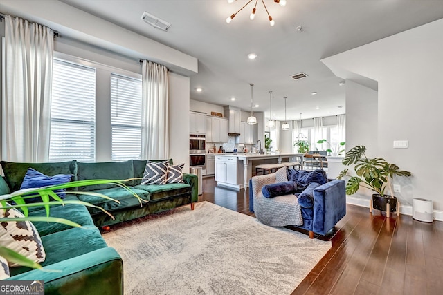 living area with a chandelier, dark wood-style floors, baseboards, and recessed lighting