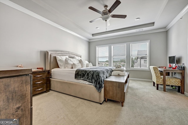 bedroom featuring a tray ceiling, light colored carpet, baseboards, ornamental molding, and a ceiling fan