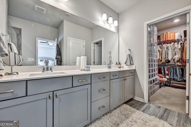 bathroom with double vanity, ceiling fan, a walk in closet, and wood tiled floors