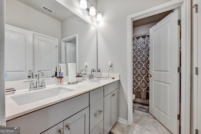 bathroom with double vanity, toilet, a shower with shower curtain, and baseboards