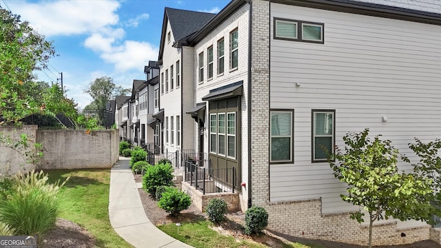 view of side of home featuring brick siding and fence