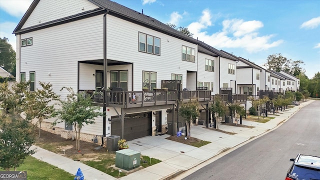 view of front facade featuring a residential view, central AC unit, a garage, and concrete driveway