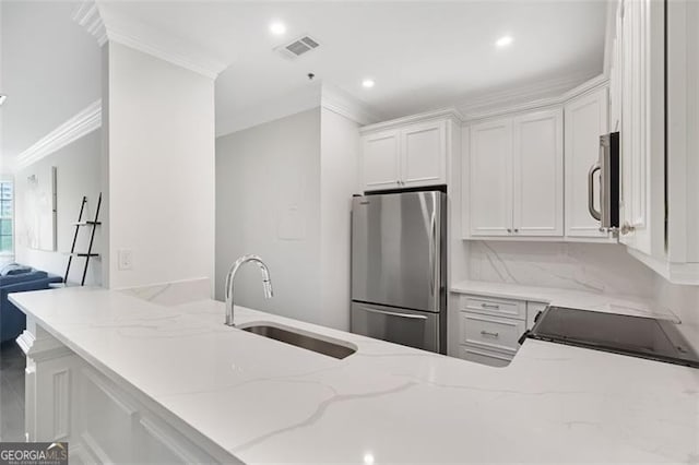 2499 Peachtree Rd NE Unit 503, Atlanta, GA 30305 - kitchen featuring appliances with stainless steel finishes, a sink, ornamental molding, light stone counters, and white cabinets