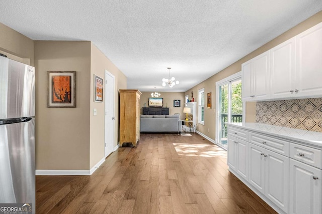 4027 Mount Vernon Dr, Woodstock, GA 30189 - kitchen featuring freestanding refrigerator, a chandelier, baseboards, tasteful backsplash, and light countertops